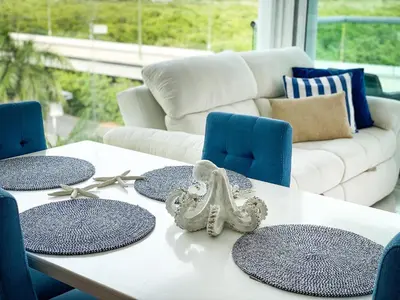 a white table with blue chairs and a white couch at Apartamento Cartagena en Morros frente a la playa in Cartagena de Indias