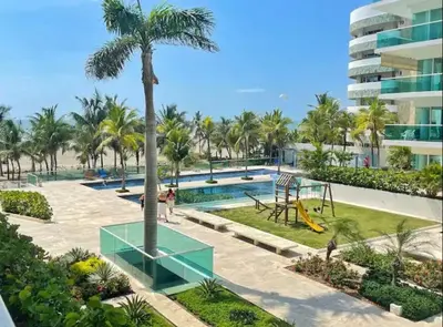 a resort pool with a palm tree and a slide at Apartamento con excelente vista al mar Dos alcobas los Morros in Cartagena de Indias