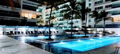 a large building with a swimming pool and palm trees at Apartamento con excelente vista al mar Dos alcobas los Morros in Cartagena de Indias