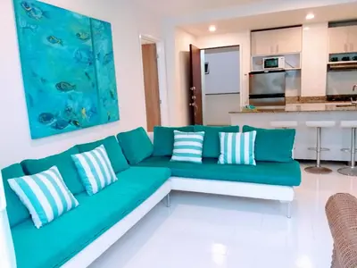 a living room with a green couch and a kitchen at Apartamento con excelente vista al mar Dos alcobas los Morros in Cartagena de Indias