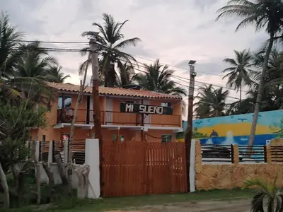 a house with a fence and palm trees at Cabaña frente al mar en moñitos, córdoba in Moñitos