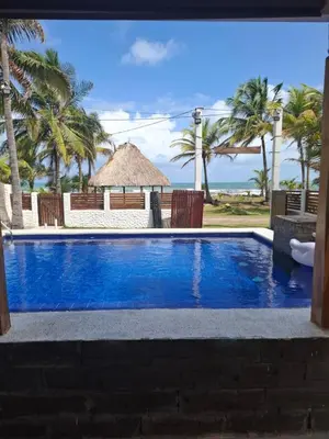 a swimming pool with a gazebo and palm trees at Cabaña frente al mar en moñitos, córdoba in Moñitos