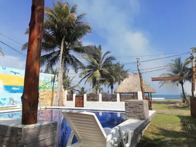 a resort with a swimming pool and palm trees and the ocean at Cabaña frente al mar en moñitos, córdoba in Moñitos