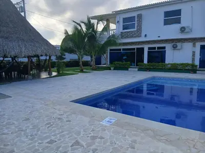 a swimming pool in front of a house at Cabaña Villa Carmen in Juan de Acosta