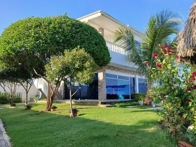 a house with a lawn and trees in front of it at Cabaña Villa Carmen in Juan de Acosta