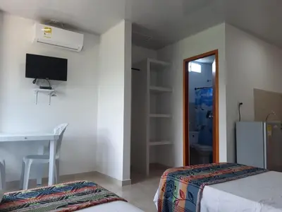 a bedroom with a bed and a desk and a television at Cabaña Villa Carmen in Juan de Acosta