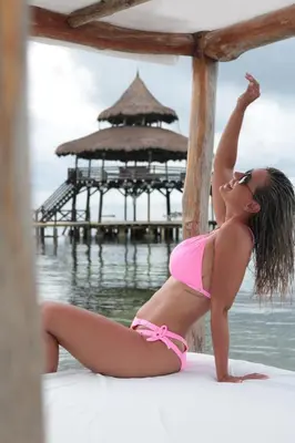 a woman in a pink bikini sitting on a pier at El Embrujo Tintipan in Tintipan Island