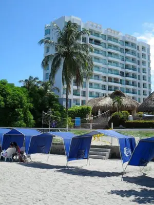 a group of blue umbrellas on a beach with a building at Costazul Suites 705 in Santa Marta