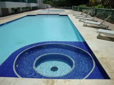 a swimming pool with a blue floor and benches at Costazul Suites 705 in Santa Marta
