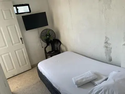 a bedroom with a white bed and a fan at sophia house in Cartagena de Indias