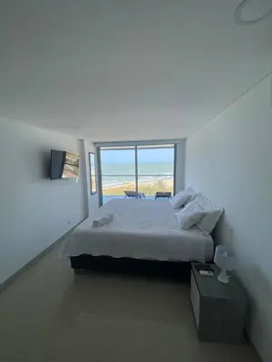 a white bedroom with a bed and a large window at Vista mar!! in Cartagena de Indias