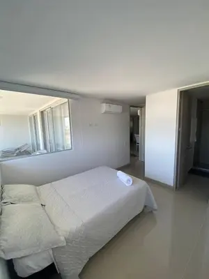 a white bedroom with a bed and a mirror at Vista mar!! in Cartagena de Indias