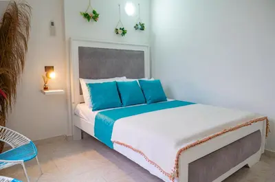 a bedroom with a large bed with blue pillows at Casa MIKONOS in Cartagena de Indias