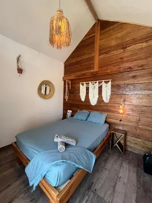 a bedroom with a bed in a room with wooden walls at Santa Lova Eco-hostel Isla Tintipan in Tintipan Island