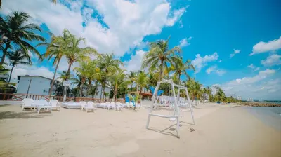 a beach with a bunch of chairs and palm trees at Kpré Coveñas by Bernalo Hotels in Coveñas