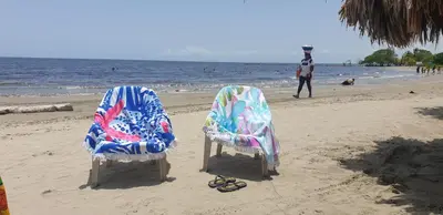 two chairs on a beach with a man in the water at Cabañas La Cuchita RNT 61621 in Coveñas