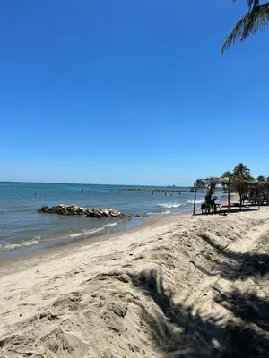 a beach with people sitting on benches and the ocean at Manglearena in Tolú