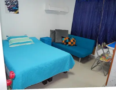 a bedroom with a blue bed and a couch at Delfin 207 in Cartagena de Indias