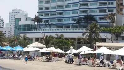 a beach with chairs and umbrellas and a building at Palmetto frente al mar 2603 in Cartagena de Indias
