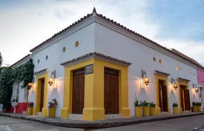 a white building with yellow doors on a street at Hotel Boutique Callecitas de San Diego in Cartagena de Indias