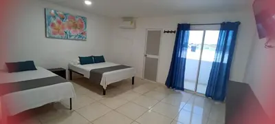a room with two beds and a window with blue curtains at Hotel La Inmaculada in Soledad