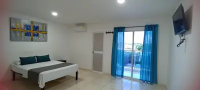 a bedroom with a bed and a window with blue curtains at Hotel La Inmaculada in Soledad