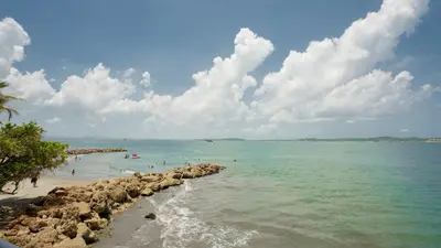 a beach with people swimming in the water at APARTESTUDIO MARINARE DE 1 HABITACION CON SALIDA DIRECTA A LA PLAYA m in Cartagena de Indias
