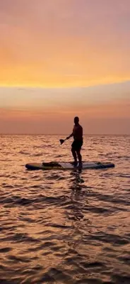 a person standing on a paddle board in the water at PLAYA LAGUITO in Cartagena de Indias
