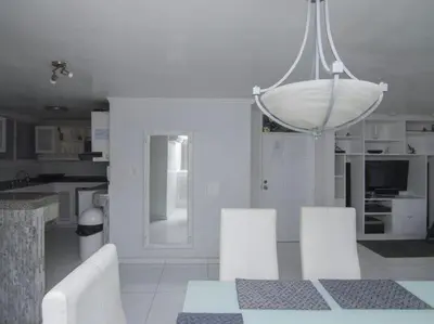 a white kitchen with a table and white chairs at PLAYA LAGUITO in Cartagena de Indias
