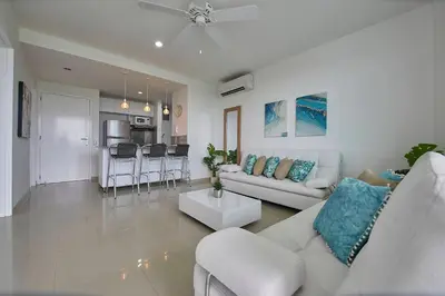 a living room with a white couch and a kitchen at Morros Pelican Sunrise - Livin Colombia in Cartagena de Indias