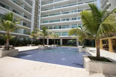 a swimming pool with palm trees in front of a building at Morros Pelican Sunrise - Livin Colombia in Cartagena de Indias
