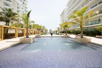 a swimming pool in front of a building with palm trees at Morros Pelican Sunrise - Livin Colombia in Cartagena de Indias