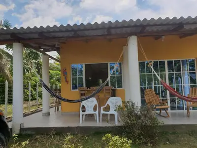 a house with two chairs and a hammock on a porch at Cabaña cerca al mar - A 200 mts in Coveñas