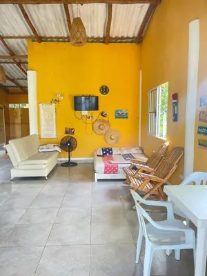 a living room with yellow walls and chairs and a tv at Cabaña cerca al mar - A 200 mts in Coveñas