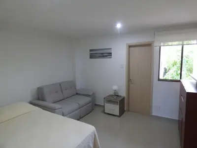 a bedroom with a bed and a couch and a window at Puesta del sol in Santa Marta