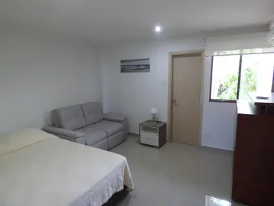a bedroom with a bed and a couch and a window at Puesta del sol in Santa Marta