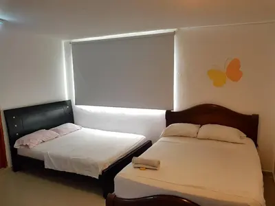 a bedroom with two beds and a window at hotel interamericano in Barranquilla