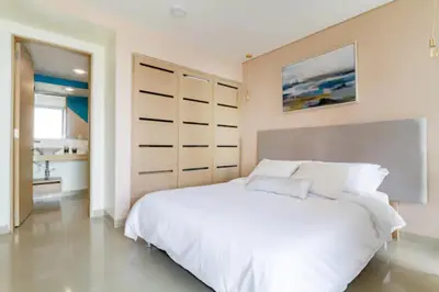 a white bedroom with a large bed and a bathroom at Paraíso en Cartagena Confort Privado con Amenidades de Hotel in Cartagena de Indias