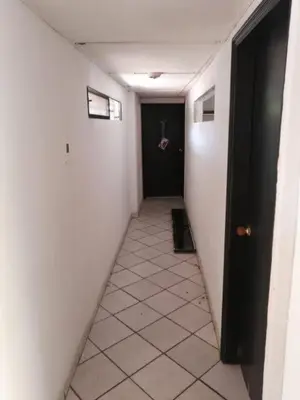 a hallway with a black door and a white tile floor at Hospedaje Altamira in Barranquilla