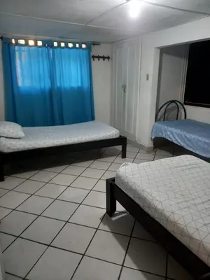 a room with two beds and a blue curtain at Hospedaje Altamira in Barranquilla