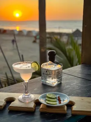 a drink on a table with a bottle of alcohol and a plate of food at Hotel Coco Beach by Croma in Cartagena de Indias