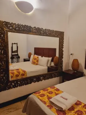 a bedroom with two beds and a mirror at Casa Cordoba Román in Cartagena de Indias