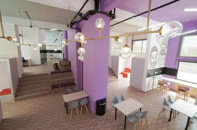 a room with purple walls and tables and chairs at LivinnX Barranquilla in Barranquilla