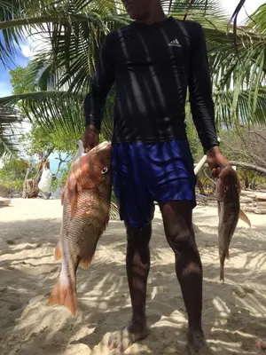 a man holding two fish on the beach at Cabaña sostenible Isla Fuerte in Isla Fuerte