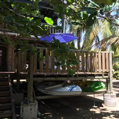 a bench with a blue umbrella next to a boat at Cabaña sostenible Isla Fuerte in Isla Fuerte