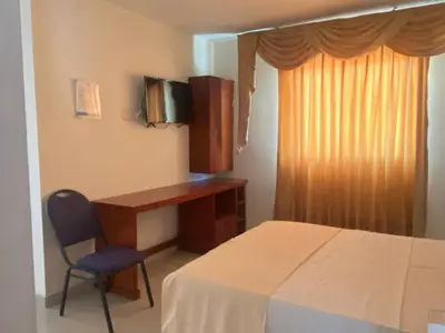 a bedroom with a desk and a bed and a chair at Hotel Rivera Del Mar in Barranquilla