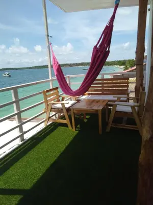 a porch with two benches and a hammock and the ocean at posada donde Uriel Playa tranquila in Baru