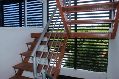a wooden staircase in front of a window at Hospedaje Mi Fortaleza, Con Piscina, Parqueadero y estamos a 10 Minutos Caminando a Playa Dormida in Santa Marta