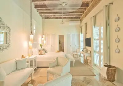 a white bedroom with a bed and two chairs at Casa Diluca Cartagena Hotel Boutique in Cartagena de Indias