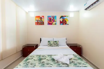 a bedroom with a bed and two paintings on the wall at Hotel Marina Suites By GEH Suites in Cartagena de Indias